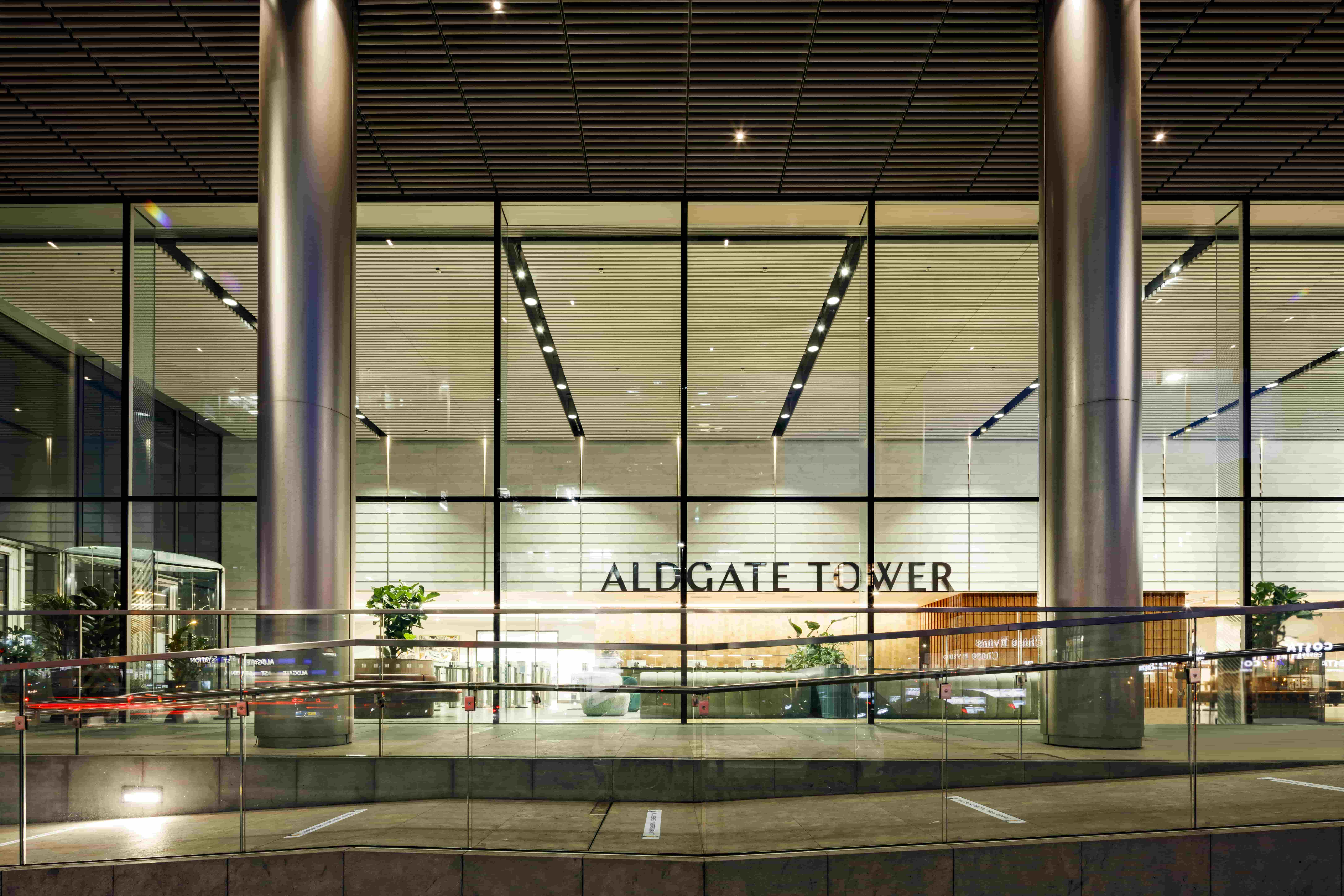 Exterior view of the lobby. The building name, Aldgate Tower, is visible through large, red windows.