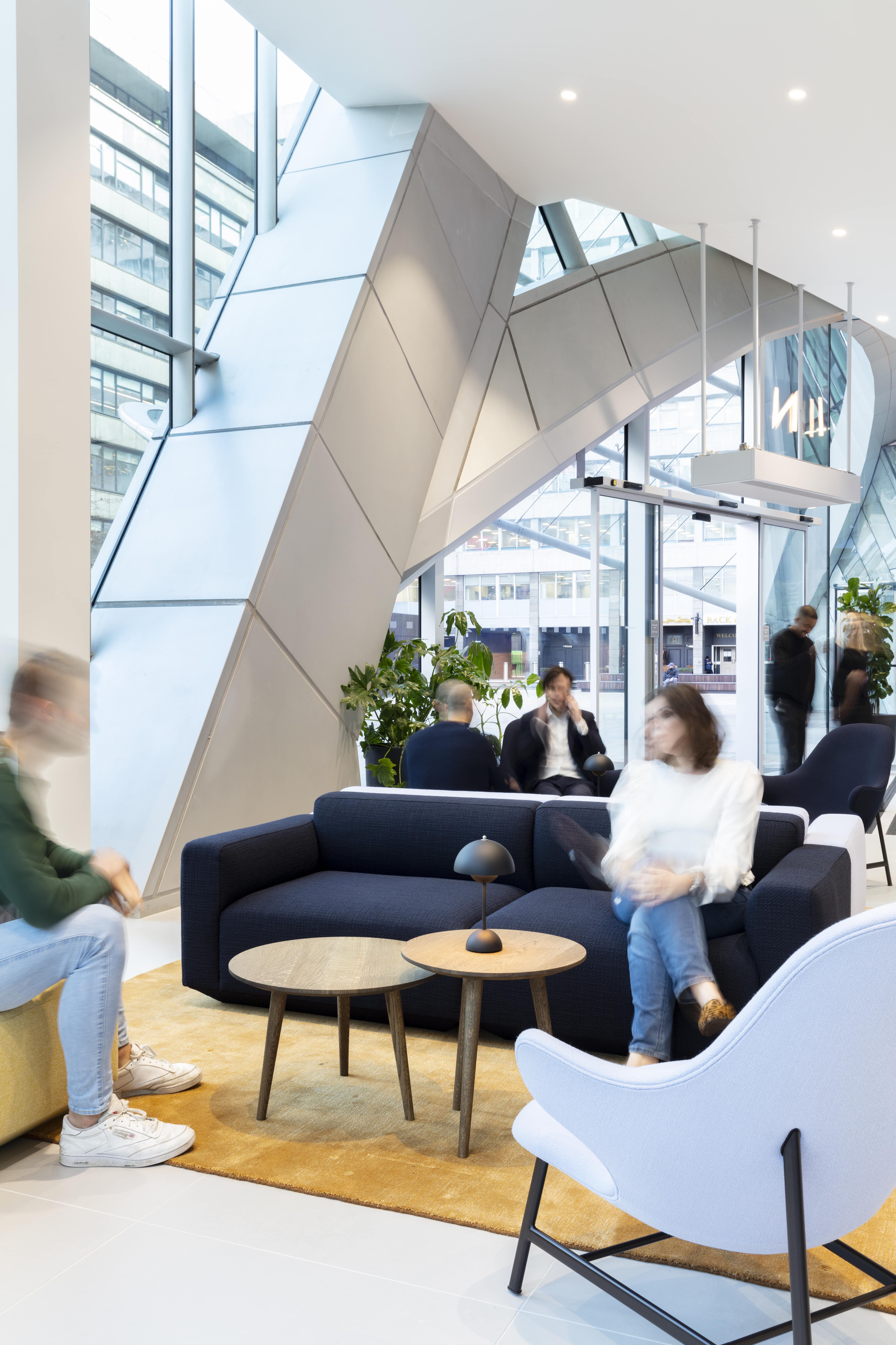 Female in white top sitting on blue couch in lobby