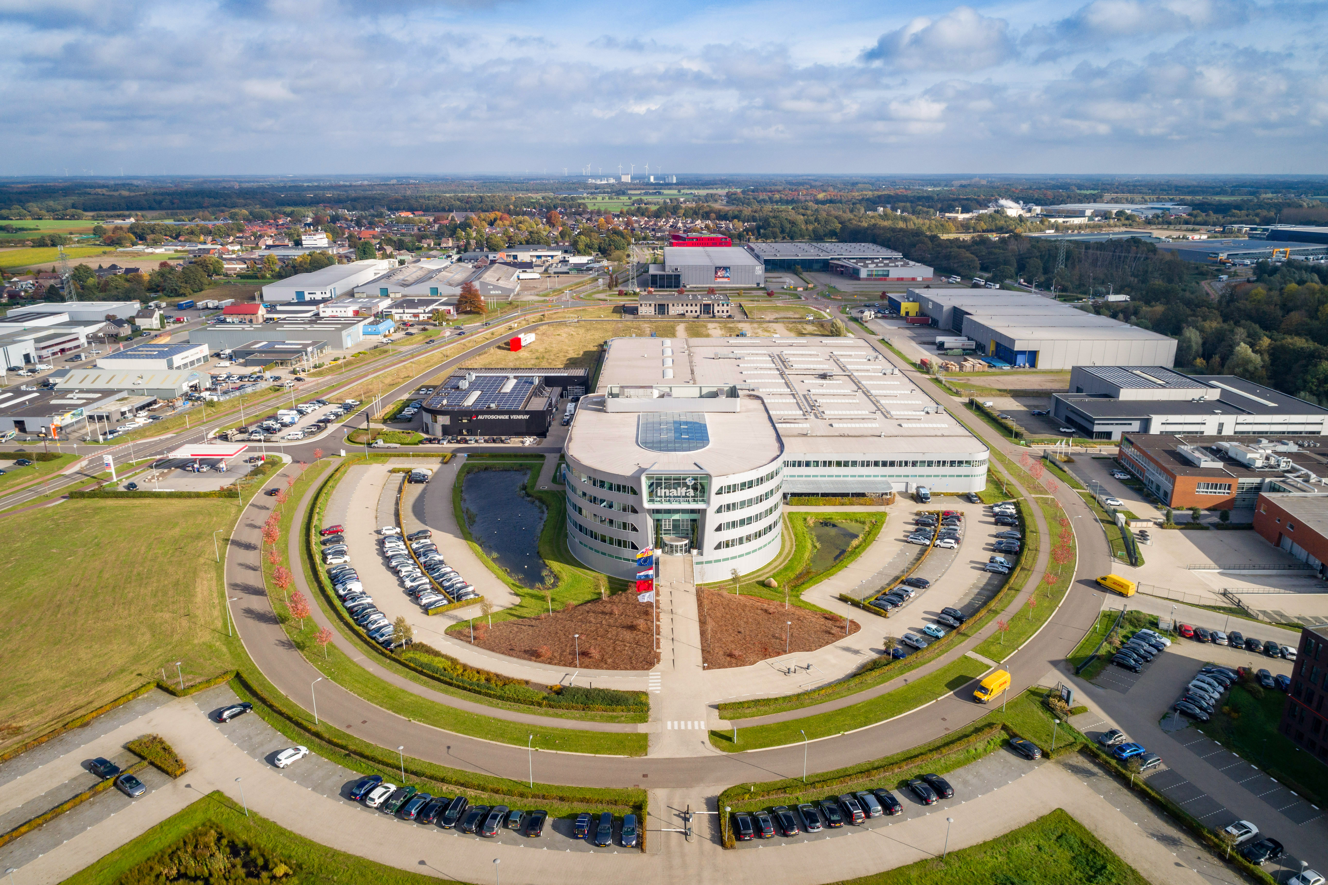 Venray - bird's eye view of logistics building surrounded by other buildings, landscaping and roadways and parking.