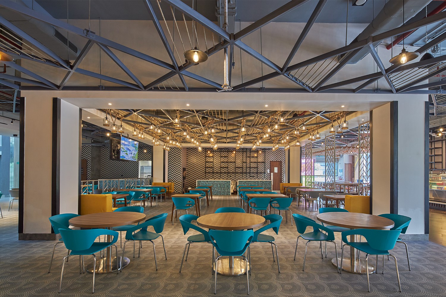 Cafeteria and lounge seating with televisions, wooden tables, and aqua colored chairs