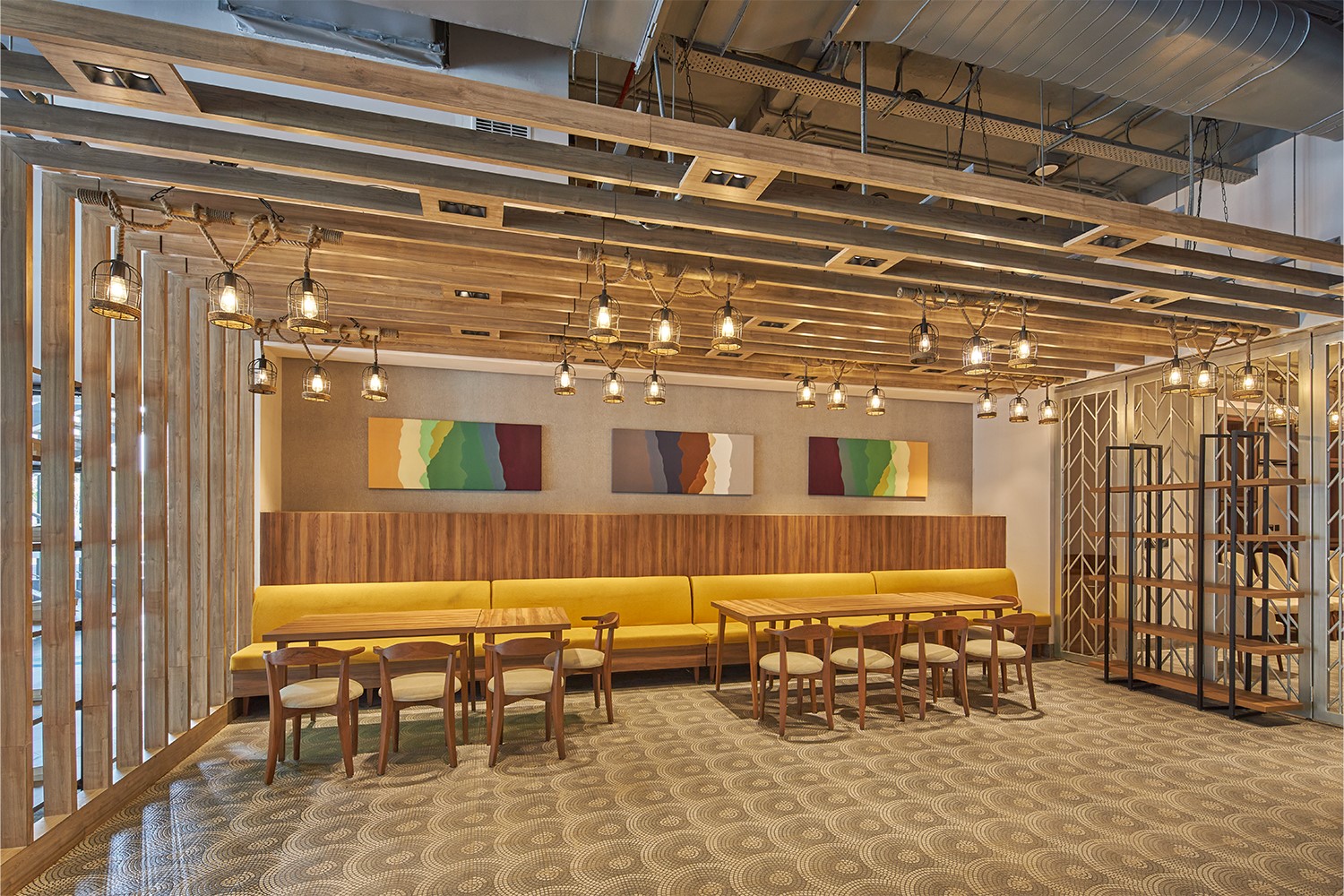 Lounge area with soft yellow benches and wooden tables with wood chairs