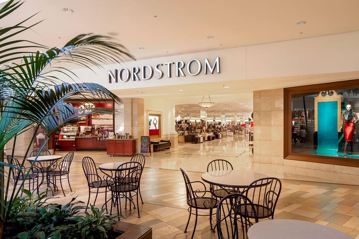 Interior of shopping center showing Nordstrom storefront with tables and chairs