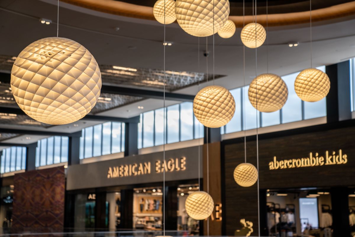 Interior of the shopping center featuring store fronts of American Eagle and abercrombie kids with hanging spherical light fixtures