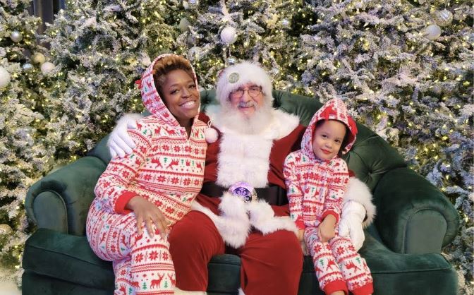 Two people sitting with Santa for a picture.